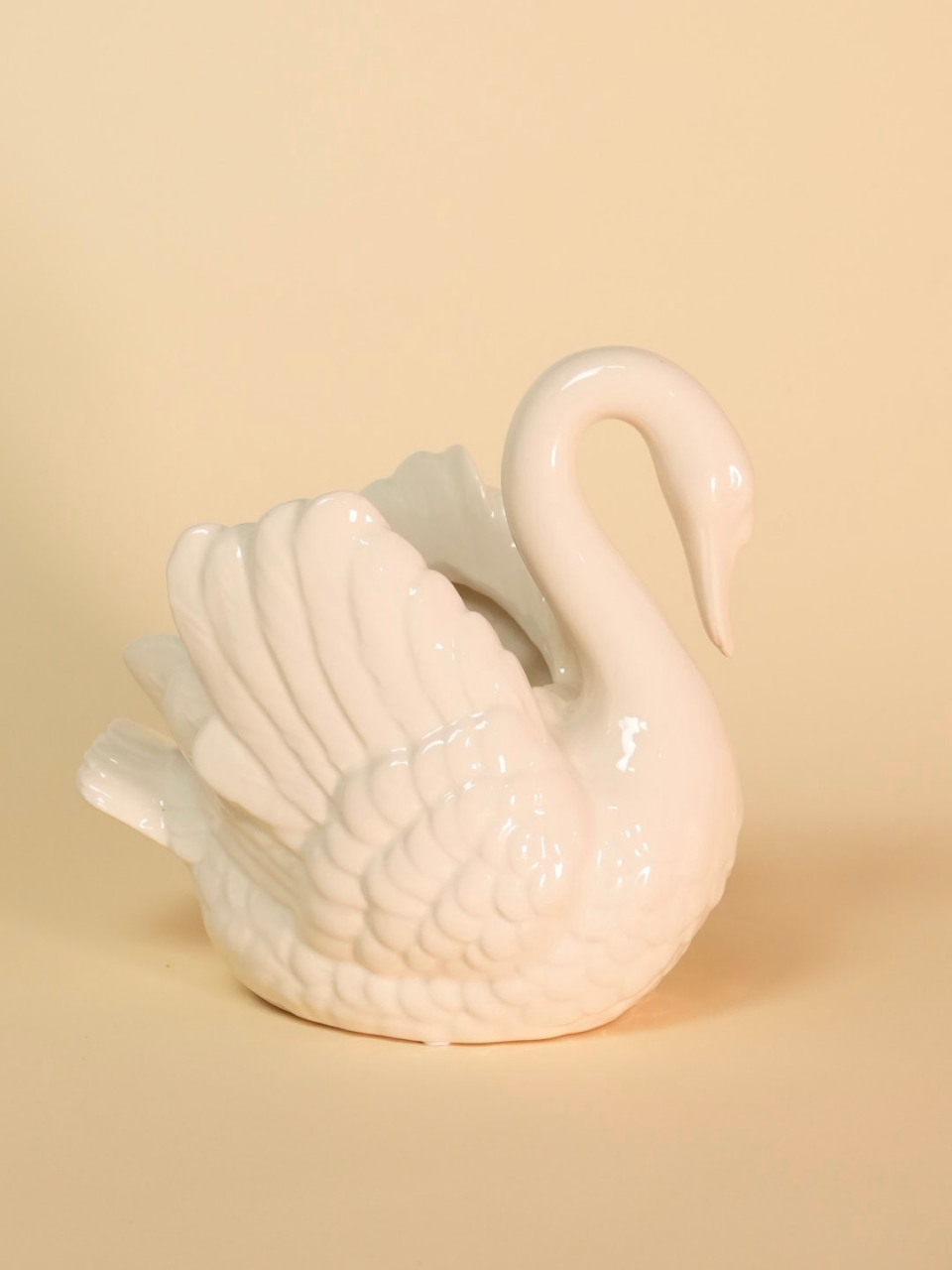 White ceramic swan on a beige background