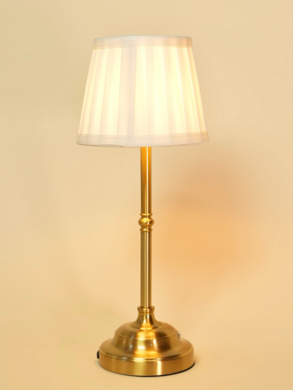 Brass floor lamp with a white shade on a beige background
