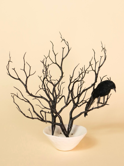 Decorative arrangement with black branches and a bird on a beige background