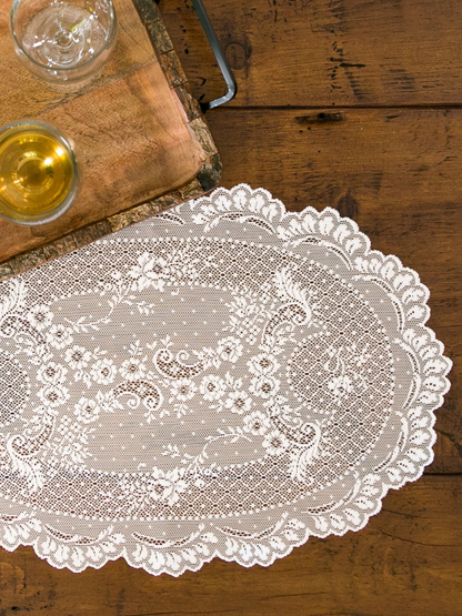 Lace doily on a wooden table with glasses of wine.