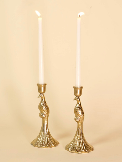Two gold candle holders with white candles on a beige background