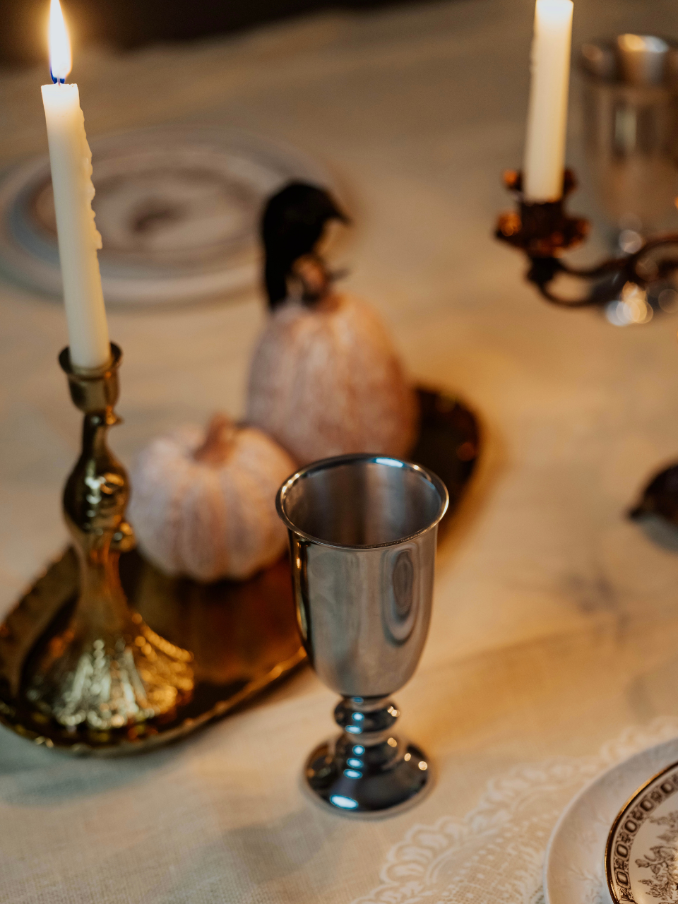 Silver goblet on a table with candles and pumpkins in the background