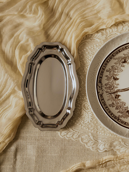 Decorative silver frame and plate on a textured beige fabric background
