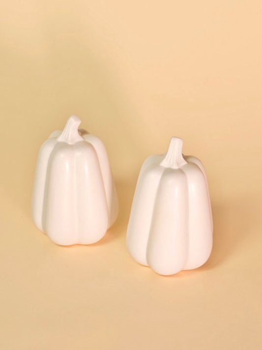 Two white ceramic pumpkins on a beige background