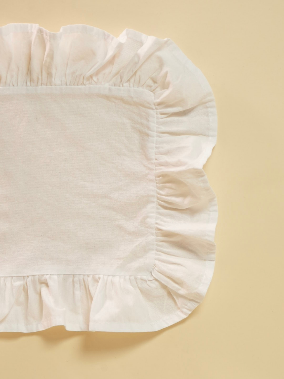White ruffled placemat on a beige background