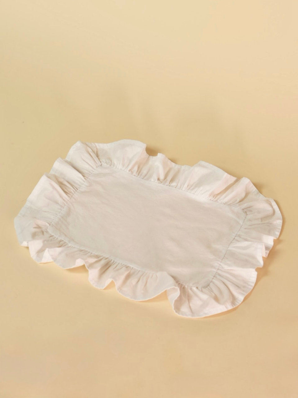 White ruffled placemat on a beige background