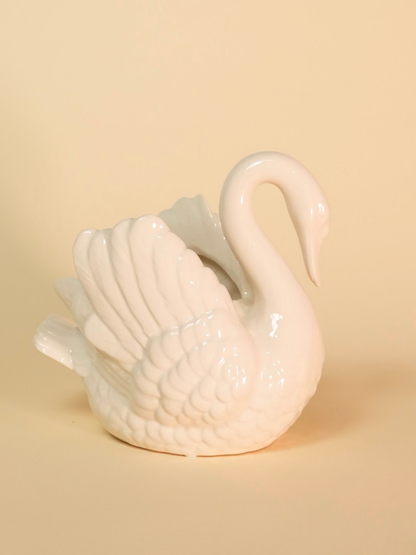 White ceramic swan on a beige background