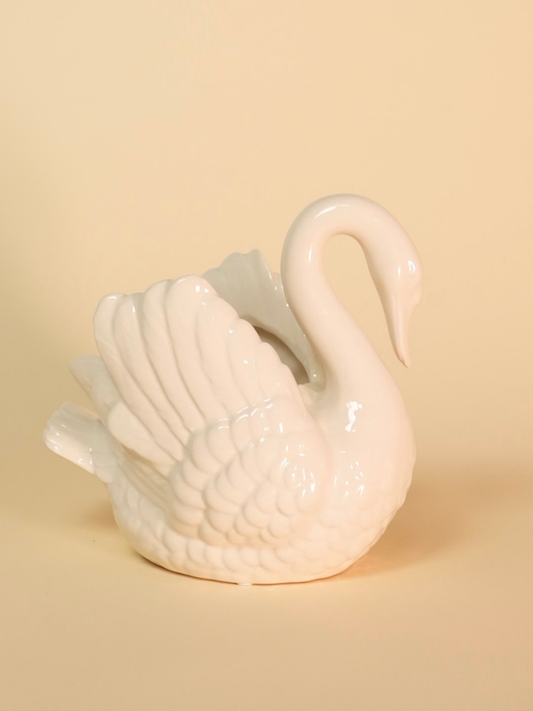 White ceramic swan on a beige background