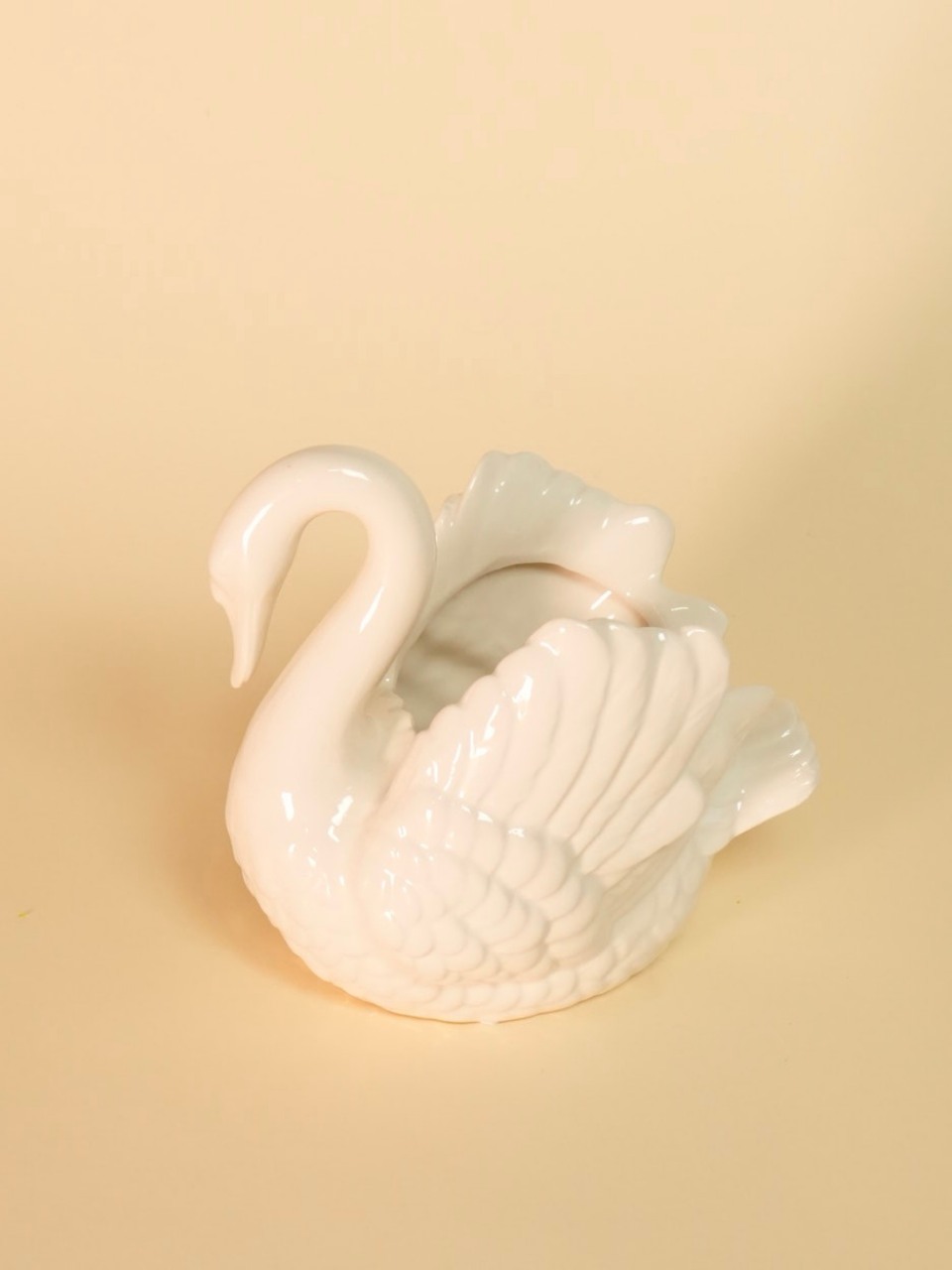 White ceramic swan on a beige background